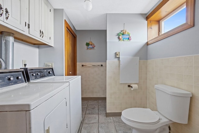 clothes washing area featuring washing machine and clothes dryer, light tile patterned floors, and tile walls