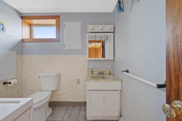 bathroom with tile patterned flooring, vanity, toilet, and tile walls