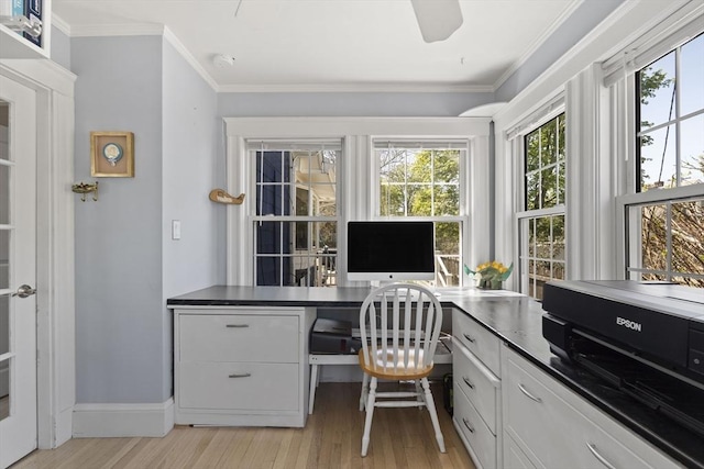 home office featuring crown molding, light wood finished floors, baseboards, and built in study area