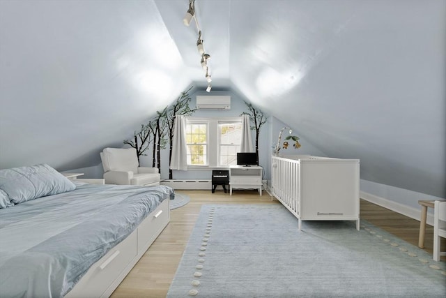 bedroom with track lighting, wood finished floors, a baseboard heating unit, a wall mounted AC, and vaulted ceiling
