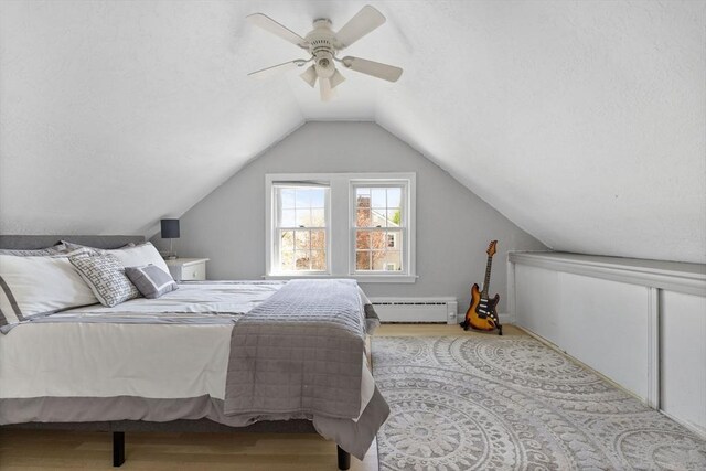 bedroom featuring a textured ceiling, a ceiling fan, a baseboard heating unit, and wood finished floors