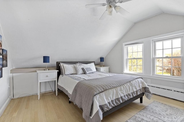 bedroom with baseboards, wood finished floors, vaulted ceiling, and baseboard heating