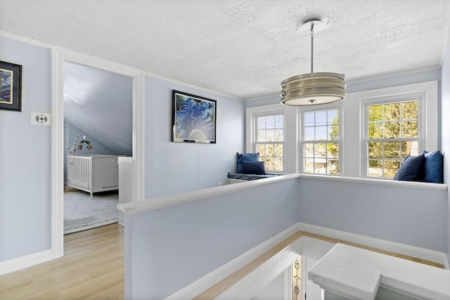 interior space featuring a textured ceiling, baseboards, and light wood-type flooring