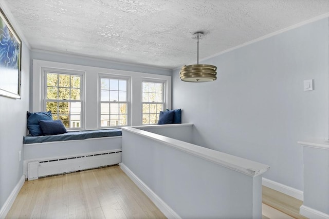 corridor with a textured ceiling, a baseboard heating unit, an upstairs landing, and light wood-style floors