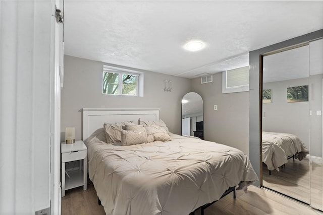 bedroom with visible vents, arched walkways, and wood finished floors