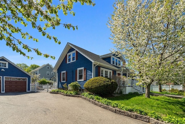view of front of home featuring a garage, fence, driveway, and a front lawn