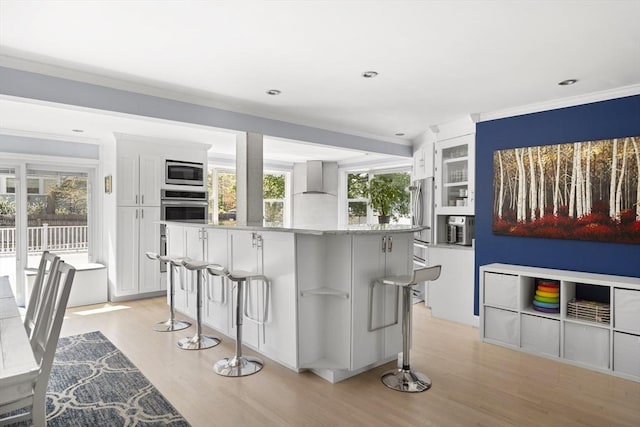 kitchen featuring a center island, light wood-type flooring, white cabinets, glass insert cabinets, and stainless steel appliances
