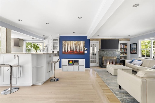 living room with crown molding, baseboards, beamed ceiling, a glass covered fireplace, and recessed lighting