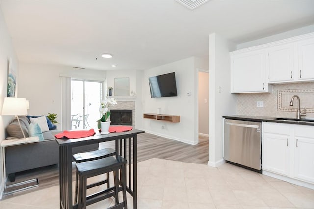 kitchen with tasteful backsplash, white cabinets, sink, and dishwasher