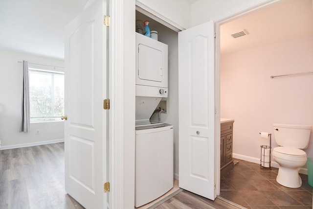 washroom featuring hardwood / wood-style flooring and stacked washing maching and dryer