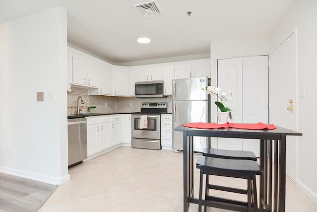 kitchen with backsplash, stainless steel appliances, sink, and white cabinets