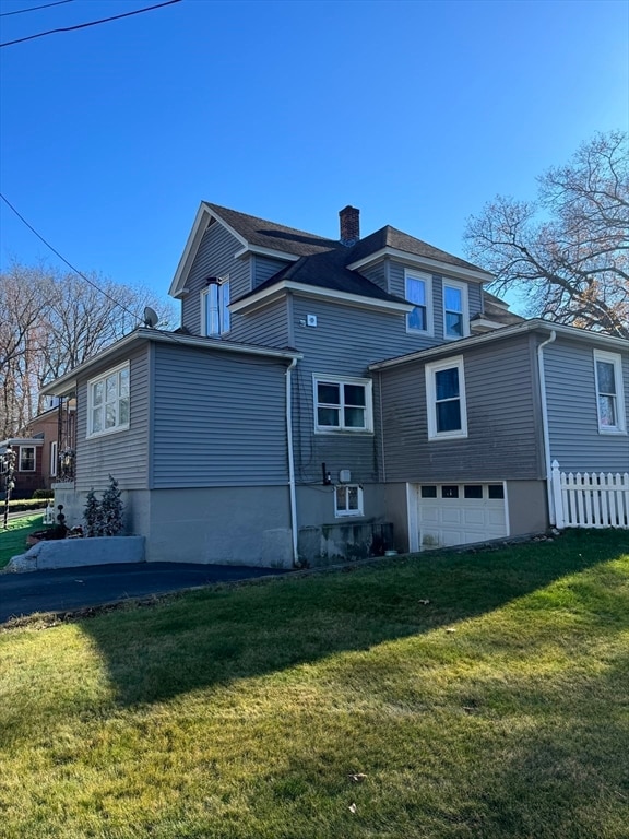 view of side of property featuring a garage and a yard