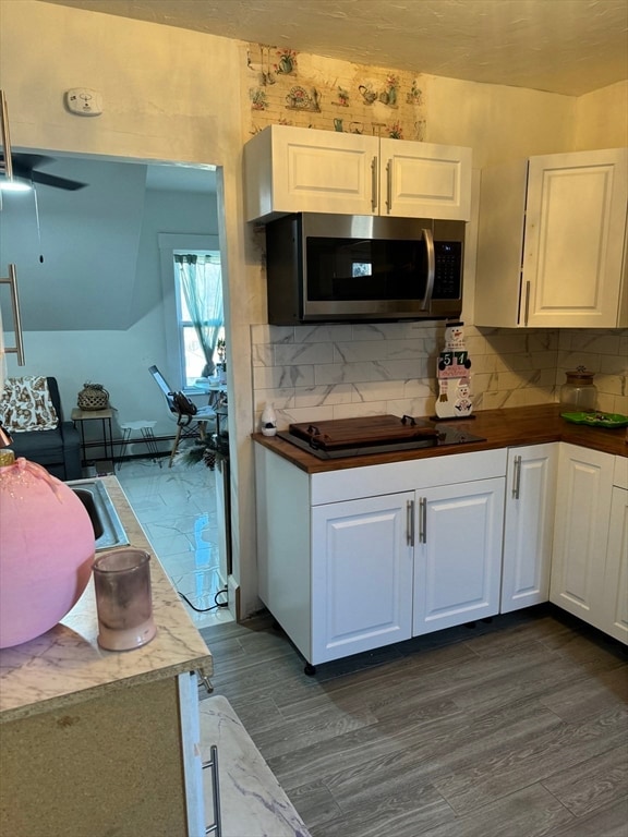 kitchen with dark wood-type flooring, white cabinetry, stovetop, and ceiling fan