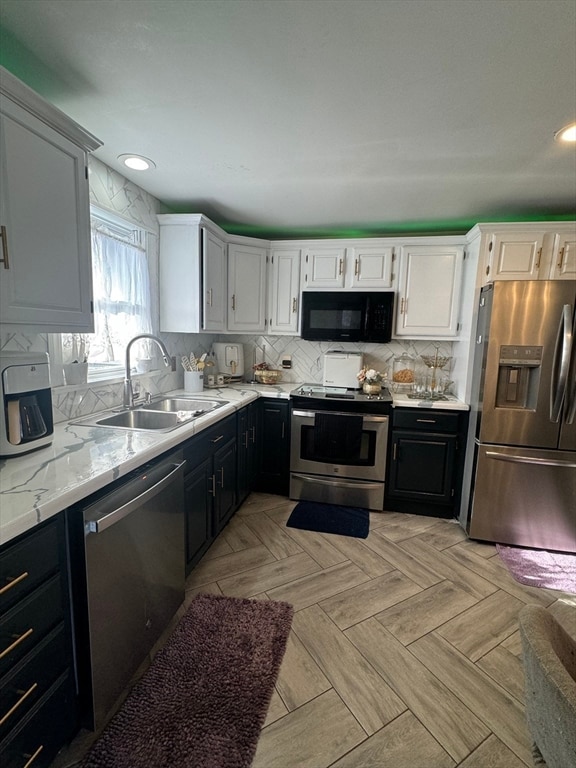 kitchen featuring stainless steel appliances, light parquet floors, sink, backsplash, and white cabinetry