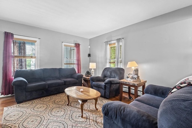 living area with wood finished floors, a baseboard heating unit, and healthy amount of natural light