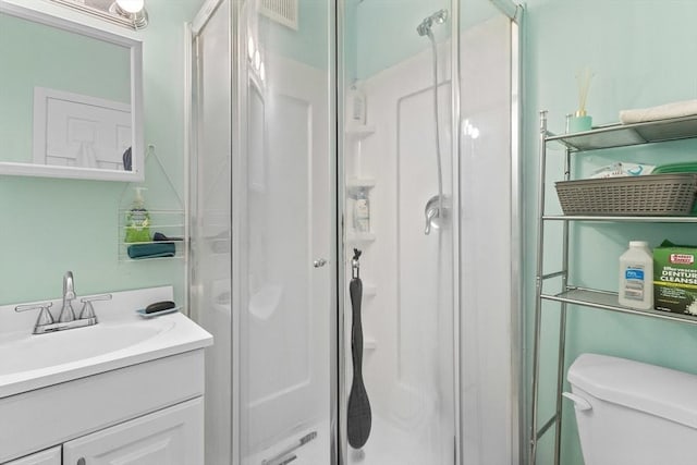 bathroom with a shower stall, toilet, and vanity