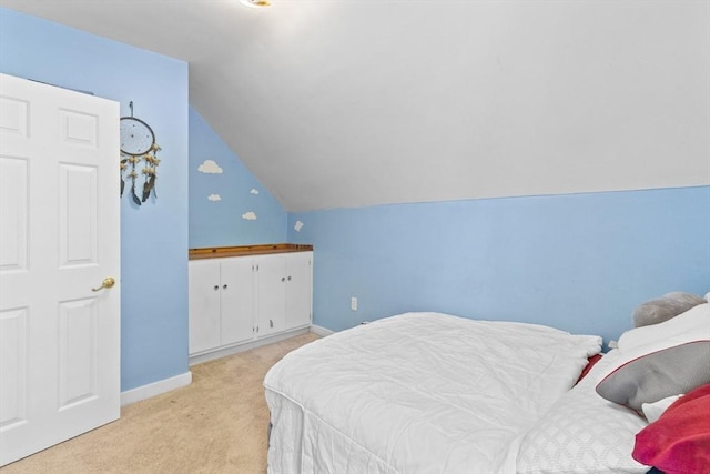 bedroom with light colored carpet, vaulted ceiling, and baseboards