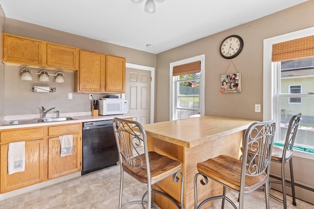 kitchen with black dishwasher, white microwave, a sink, and light countertops