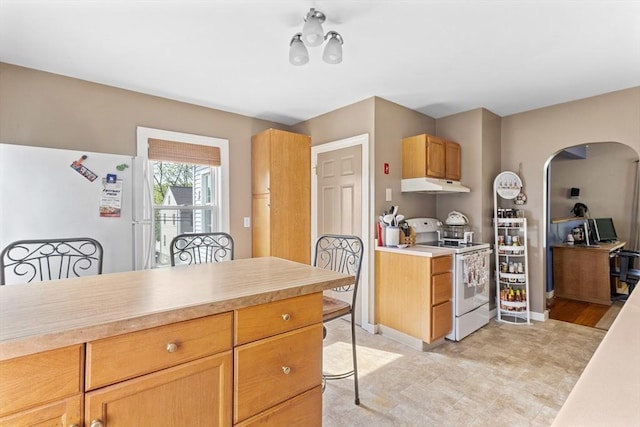 kitchen featuring white appliances, under cabinet range hood, arched walkways, and light countertops