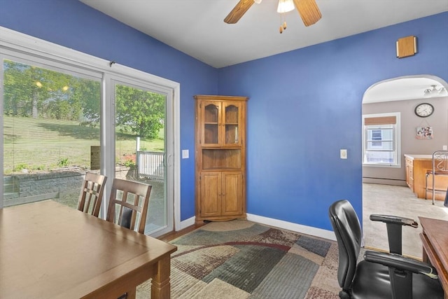 office area featuring a ceiling fan, arched walkways, plenty of natural light, and baseboards