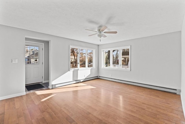 unfurnished room featuring baseboard heating, a wealth of natural light, ceiling fan, and light wood-type flooring