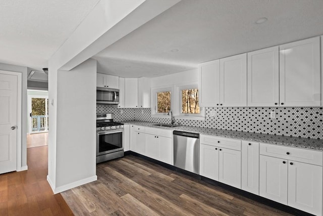 kitchen featuring dark wood-type flooring, white cabinets, sink, decorative backsplash, and stainless steel appliances