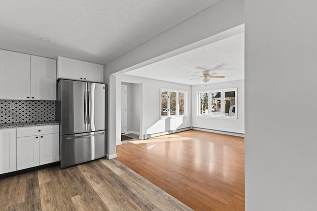 kitchen with decorative backsplash, stainless steel fridge, dark hardwood / wood-style flooring, ceiling fan, and white cabinets