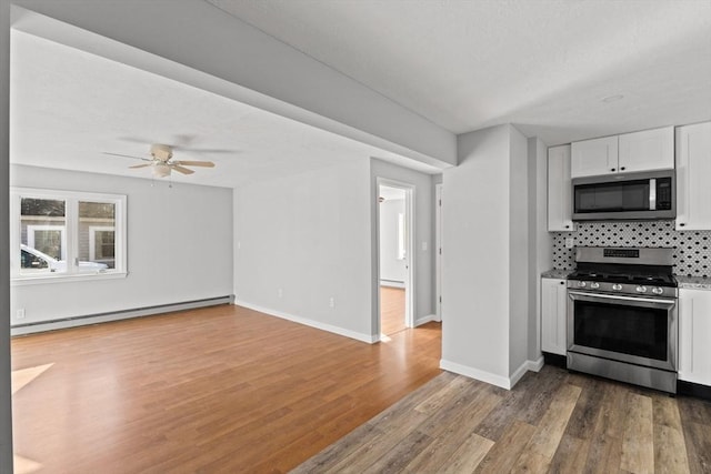 kitchen with stainless steel appliances, a baseboard radiator, tasteful backsplash, white cabinets, and hardwood / wood-style flooring