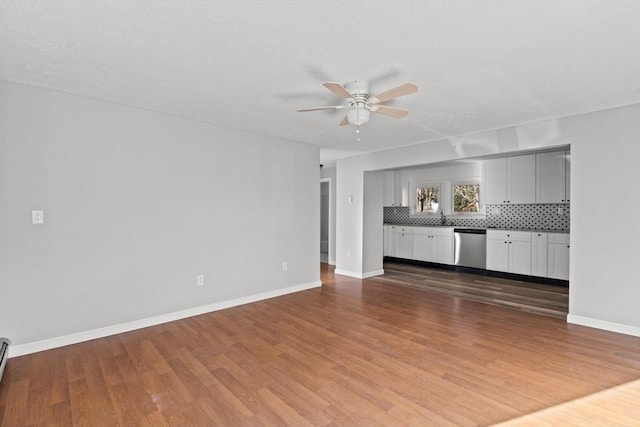 unfurnished living room with baseboard heating, ceiling fan, sink, and hardwood / wood-style flooring