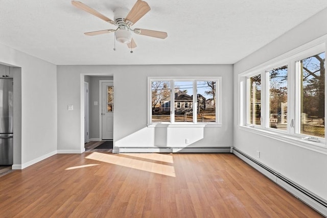 interior space featuring light wood-type flooring, a baseboard radiator, and ceiling fan