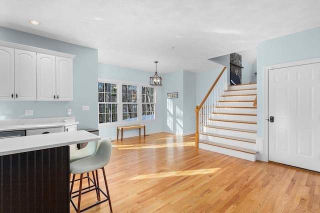 kitchen featuring pendant lighting, light hardwood / wood-style floors, white cabinetry, and a kitchen breakfast bar