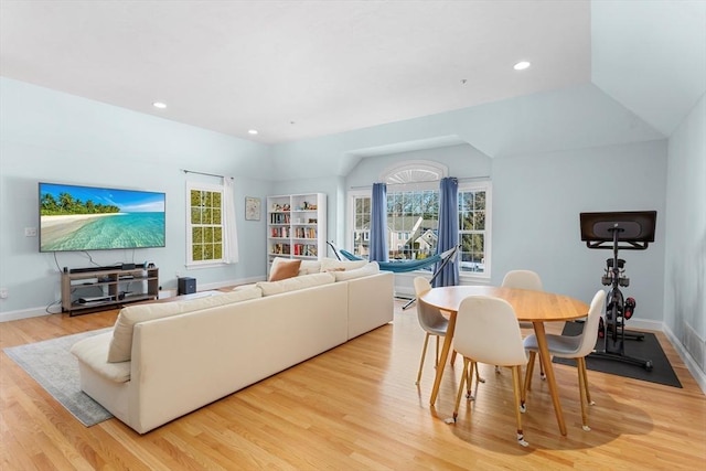 living room with plenty of natural light, light hardwood / wood-style floors, and lofted ceiling