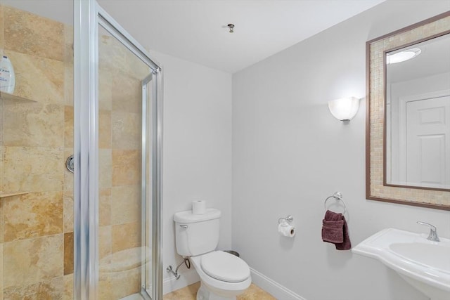 bathroom featuring sink, a shower with shower door, and toilet