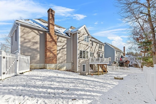 snow covered rear of property featuring a deck