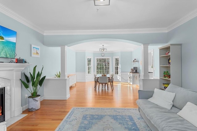 living room featuring light wood-type flooring, crown molding, and a high end fireplace