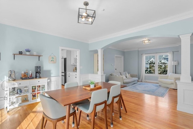 dining area featuring ornate columns, crown molding, and light hardwood / wood-style floors