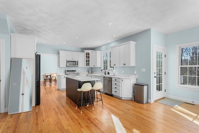 kitchen featuring white cabinets, a kitchen breakfast bar, stainless steel appliances, and a kitchen island