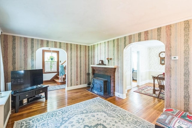 22 Sycamore Rd, Weymouth, MA 02190 - living area featuring arched walkways, wood finished floors, wallpapered walls, ornamental molding, and a wood stove