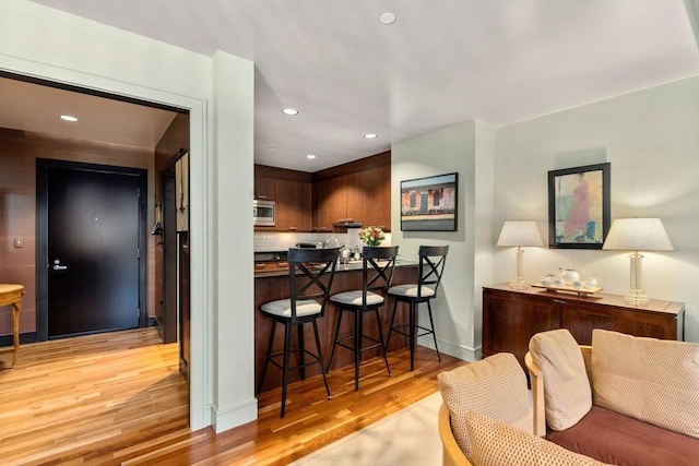 2400 Beacon St Unit 203, Boston, MA 02467 - kitchen featuring light wood-style flooring, stainless steel microwave, a kitchen breakfast bar, recessed lighting, and baseboards