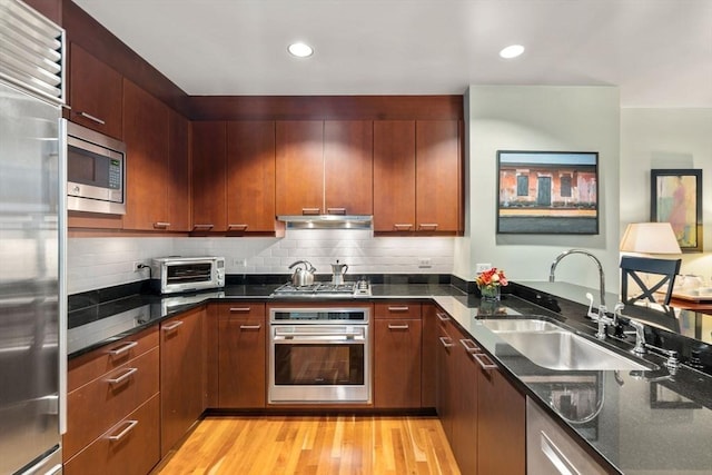 2400 Beacon St Unit 203, Boston, MA 02467 - kitchen with built in appliances, a sink, under cabinet range hood, light wood finished floors, and dark stone counters