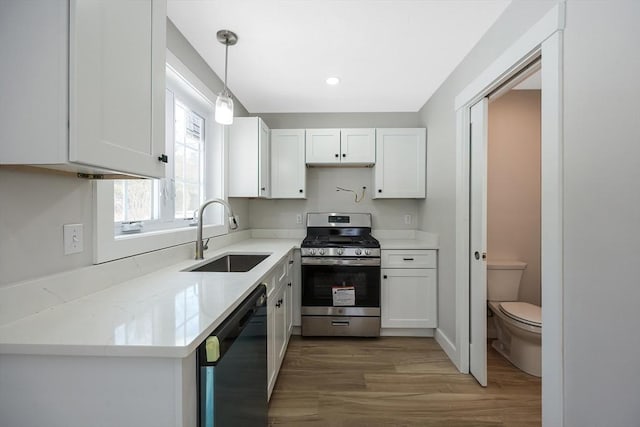 kitchen featuring sink, dishwasher, hanging light fixtures, white cabinets, and gas range