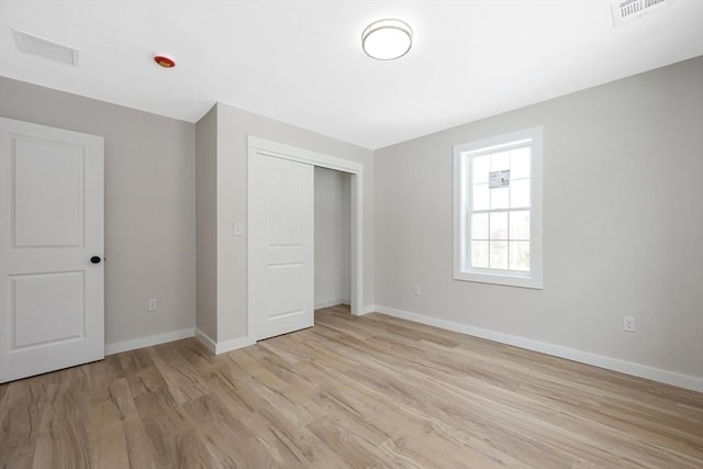 unfurnished bedroom with light wood-type flooring and a closet