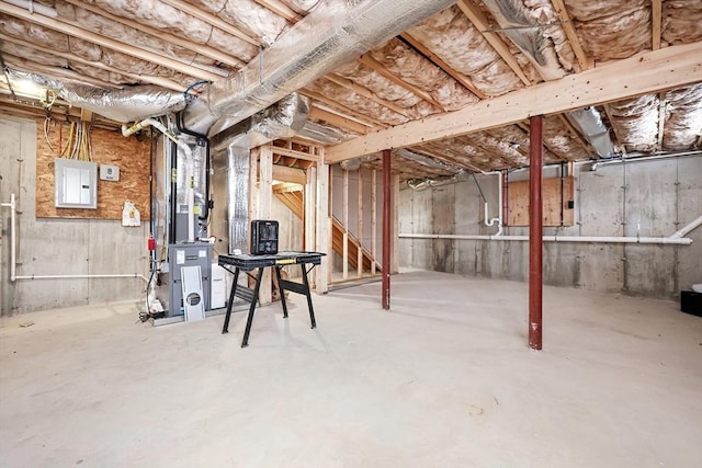 basement featuring electric panel and heating unit