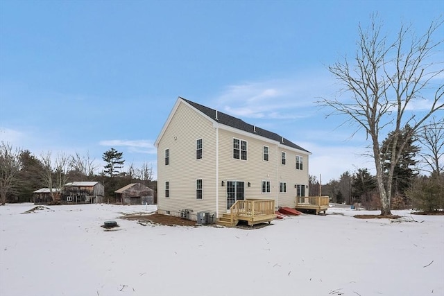 snow covered house featuring cooling unit and a deck