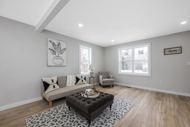 living room featuring beamed ceiling and light wood-type flooring