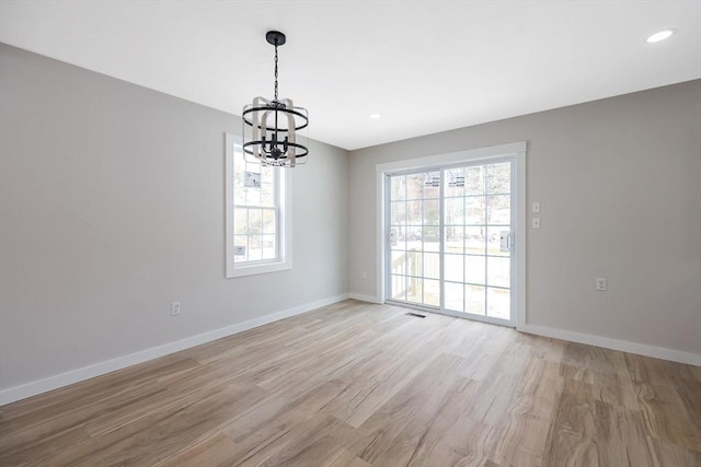 unfurnished room with light hardwood / wood-style floors and a notable chandelier