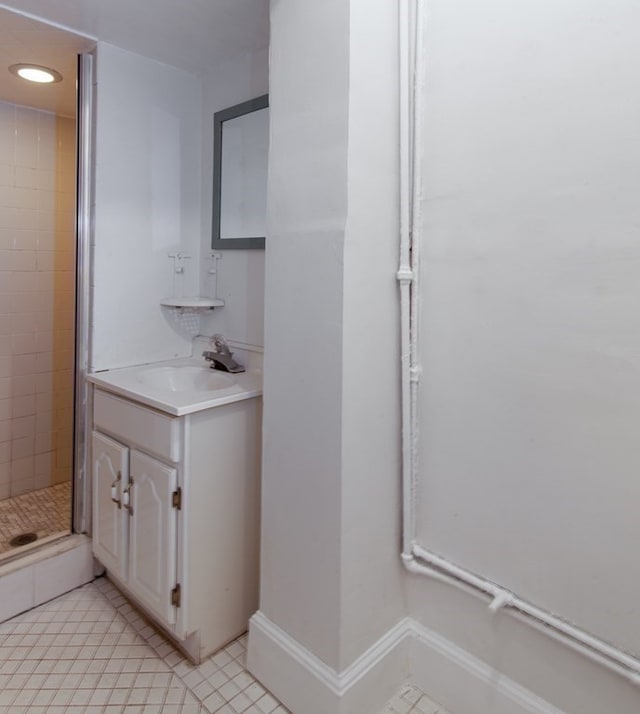 bathroom featuring tile patterned flooring, vanity, and a tile shower