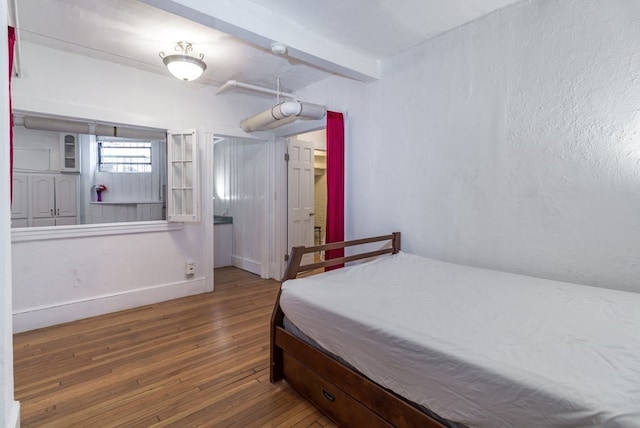 bedroom featuring beamed ceiling and hardwood / wood-style flooring