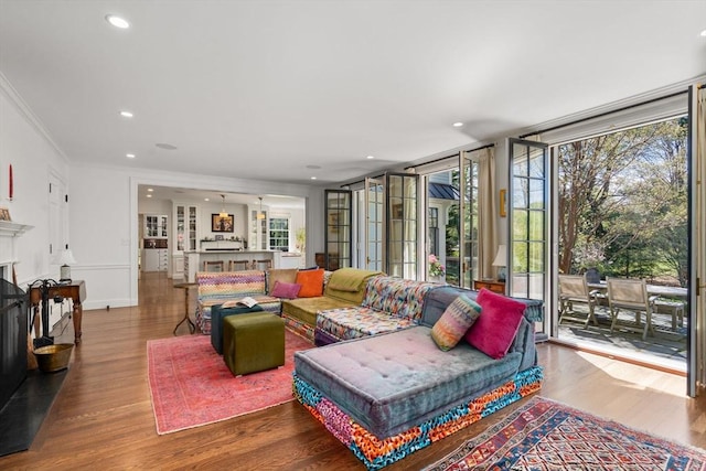 living room with a fireplace, wood finished floors, ornamental molding, recessed lighting, and floor to ceiling windows
