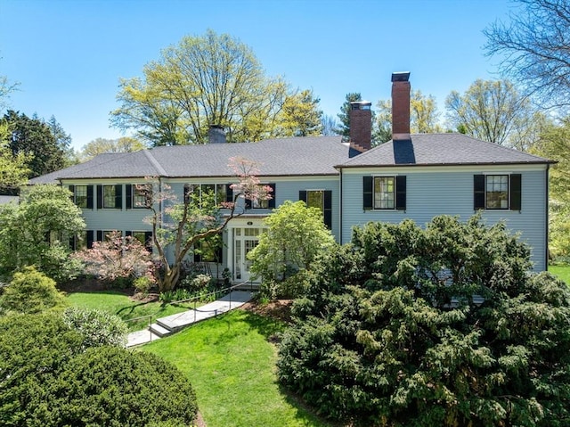 rear view of property featuring a chimney and a yard